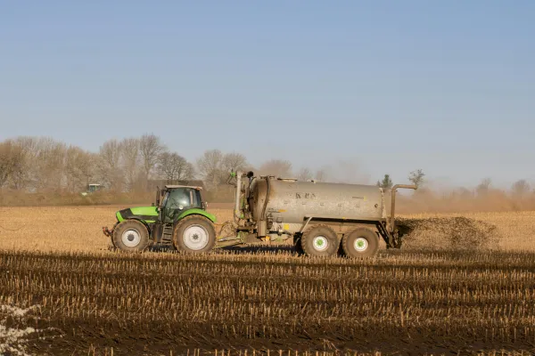 Das Bild zeigt einen Traktor beim Düngen eines Feldes. 